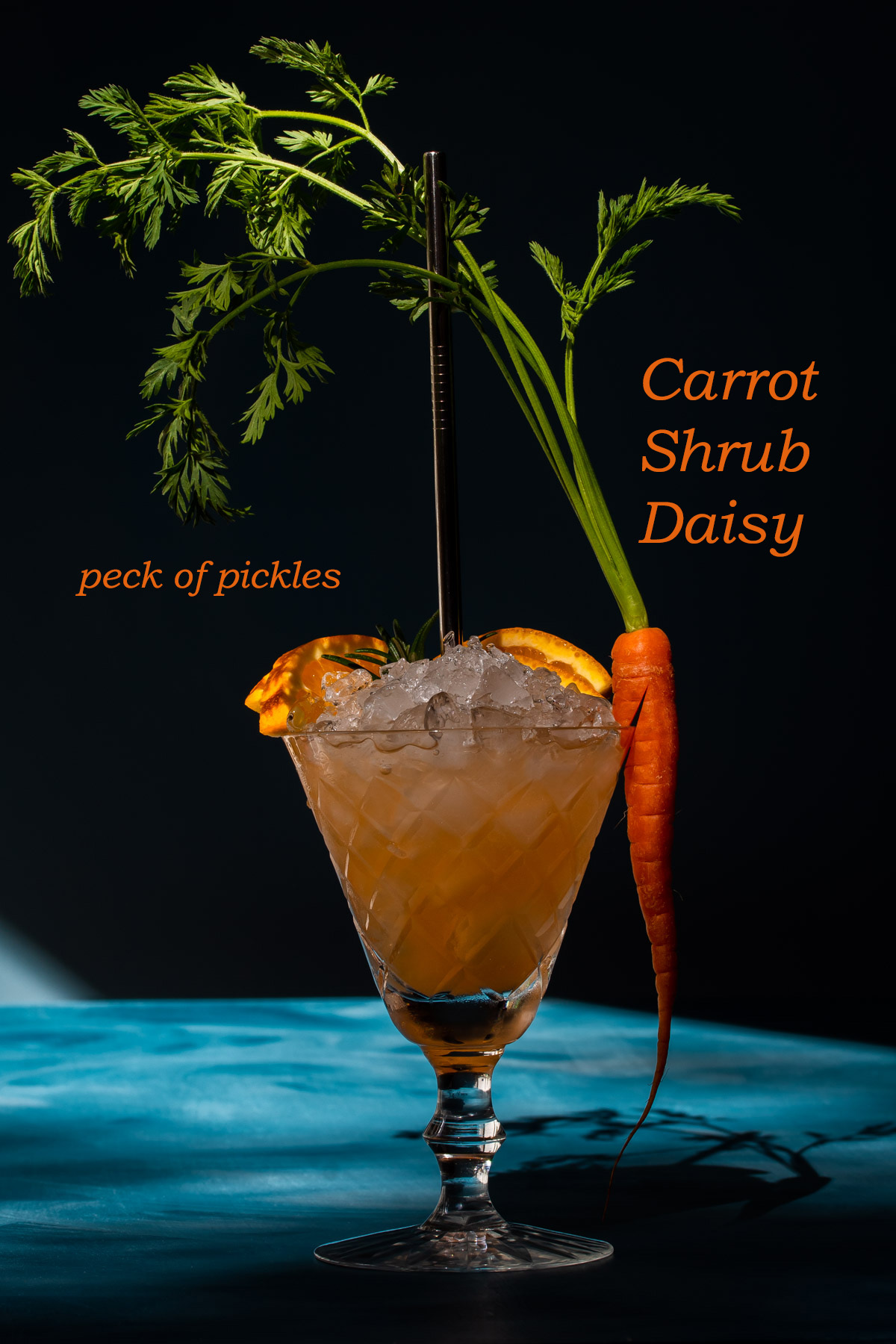 carrot shrub daisy cocktail with deep shadows on blue background