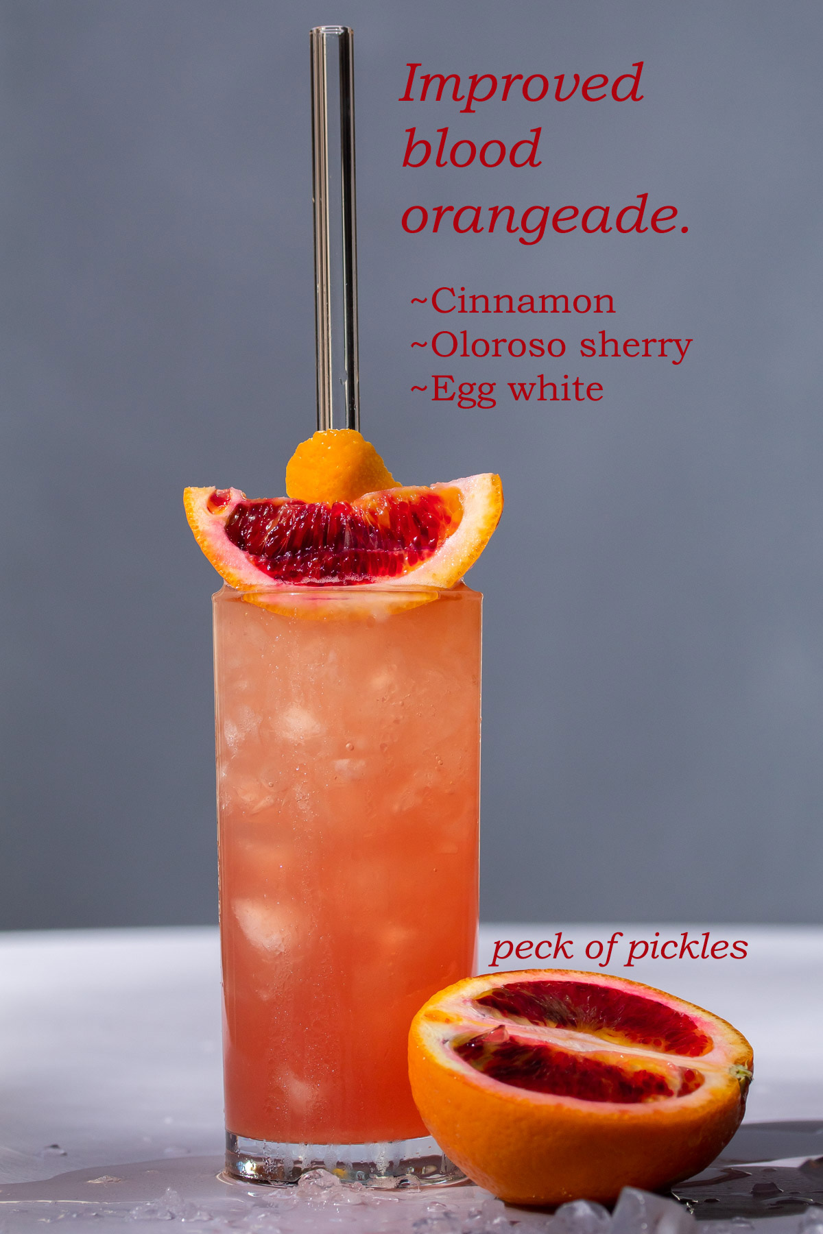 improved blood orangeade with blood orange on light purple and grey background