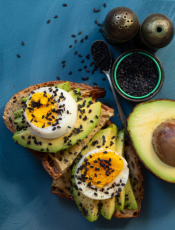 avocado toasts with hard boiled eggs blue background