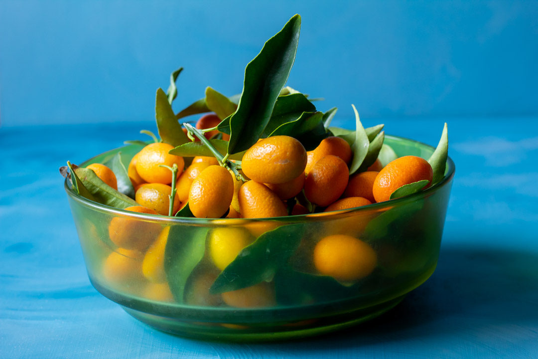 cumquats in green glass bowl