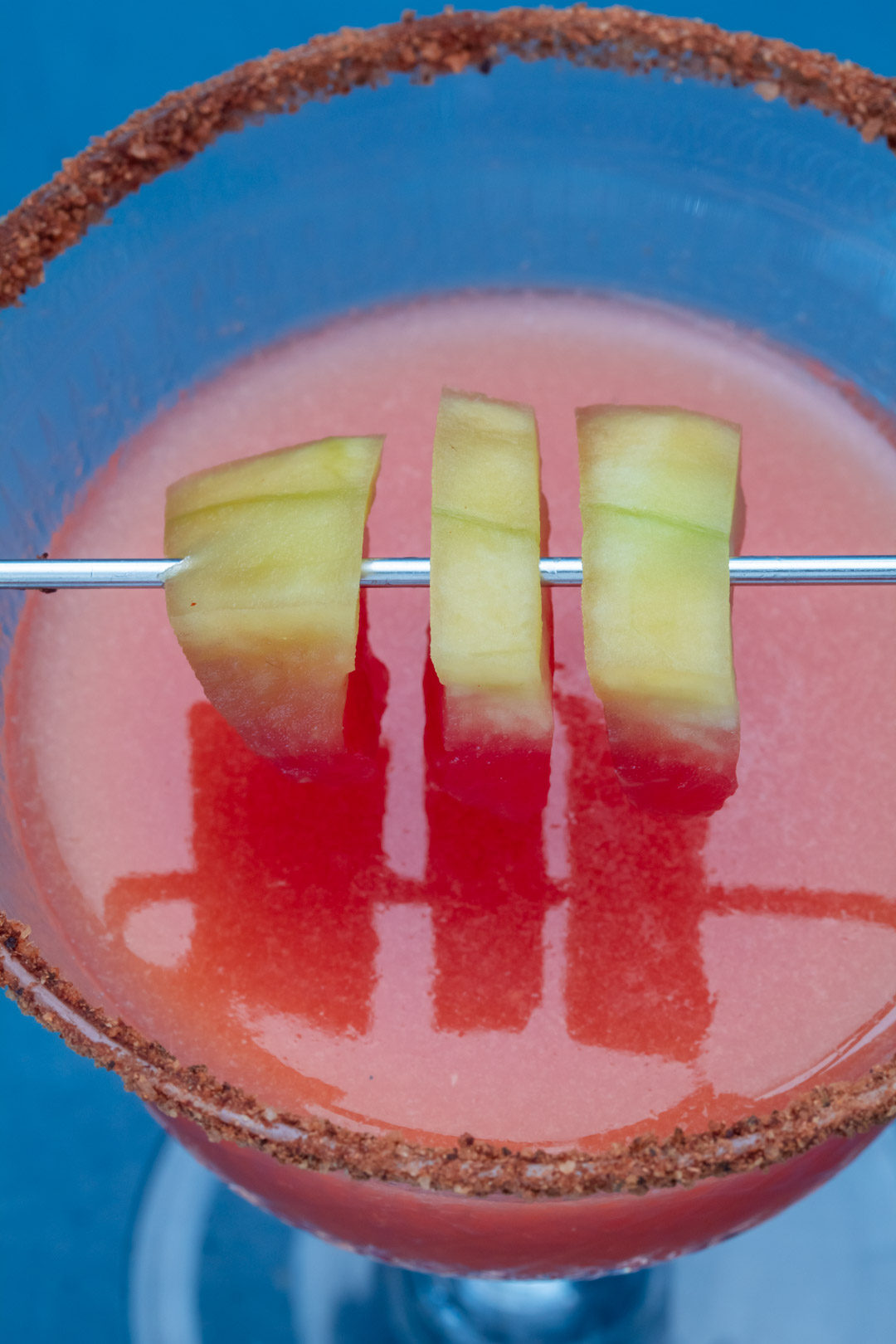 Pickled watermelon rind margarita cocktail with chili-lime-cinnamon salt: pickle reflections on surface of drink