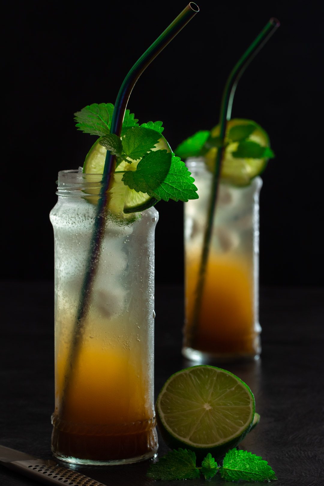 Ginger lime shrub syrup drinking vinegar: lime, lemon balm and knife in foreground