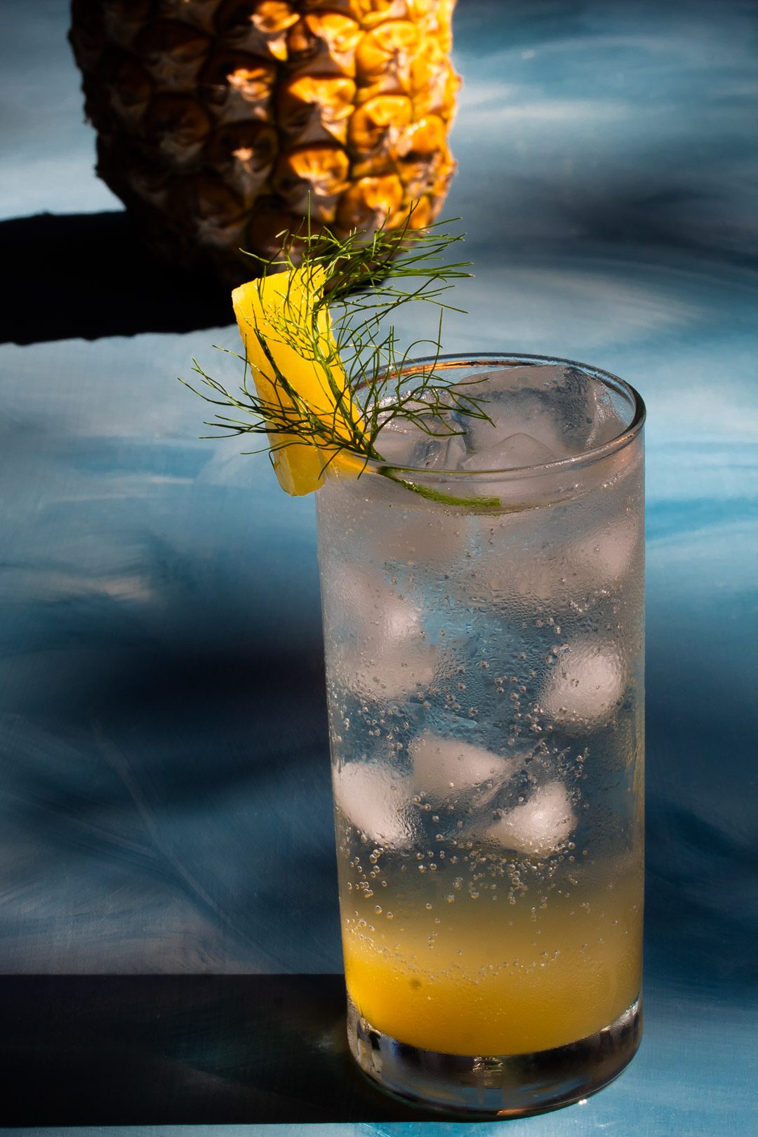 pineapple fennel shrub syrup from a 45 degree angle with pineapple in the background