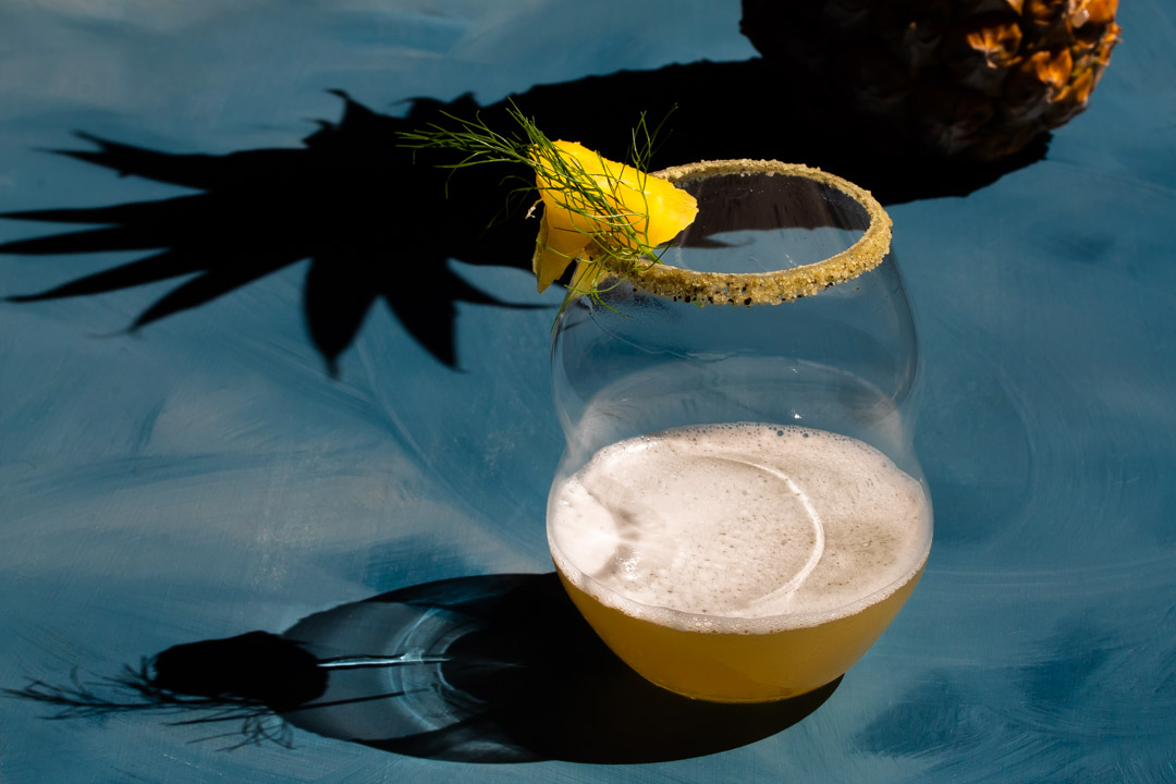 pineapple fennel shrub margarita cocktail with pineapple shadow framing glass