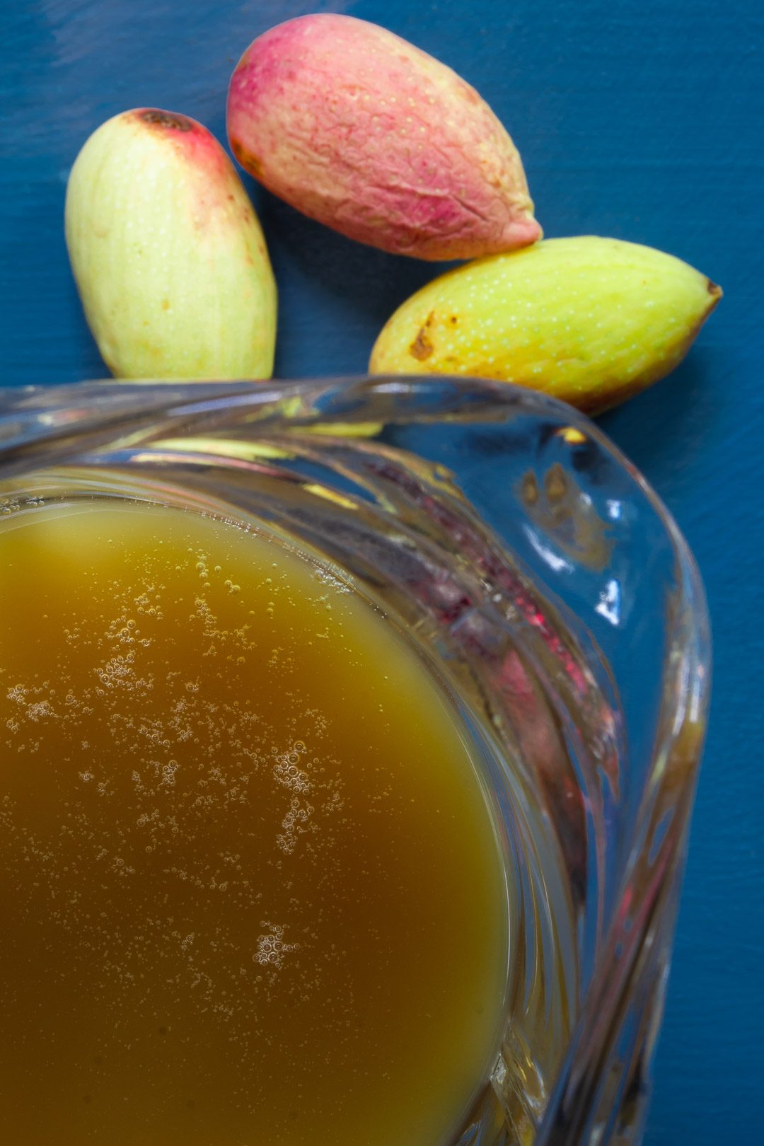 pistachio rose water orgeat syrup in glass jug from above with fresh pistachios