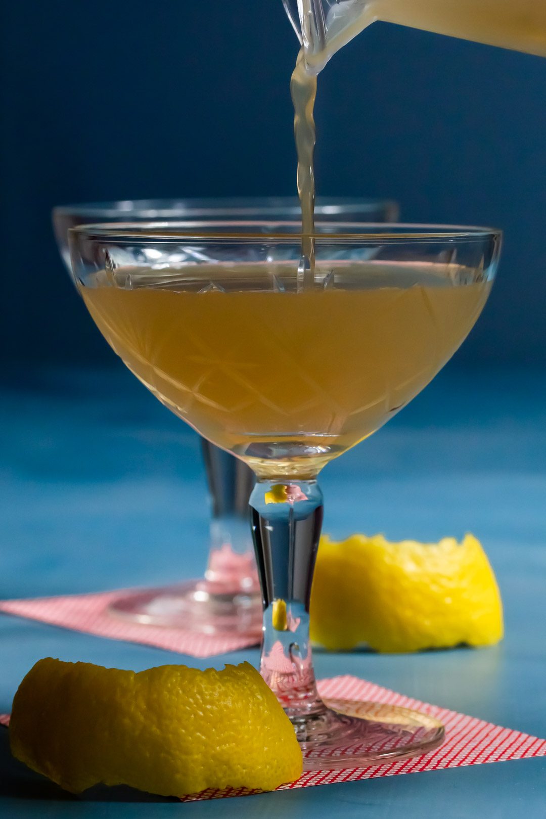 pouring a pistachio rose rhubarb Japanese cocktail with glass almost full