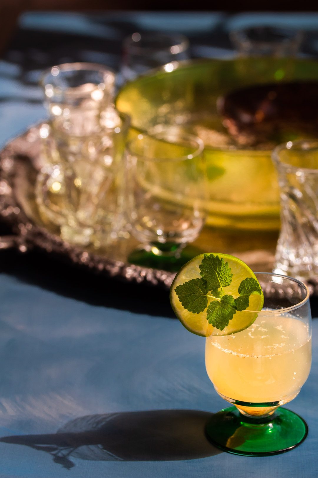 lime, matcha tea, nutmeg, lemon balm with glasses in background from 45 degrees