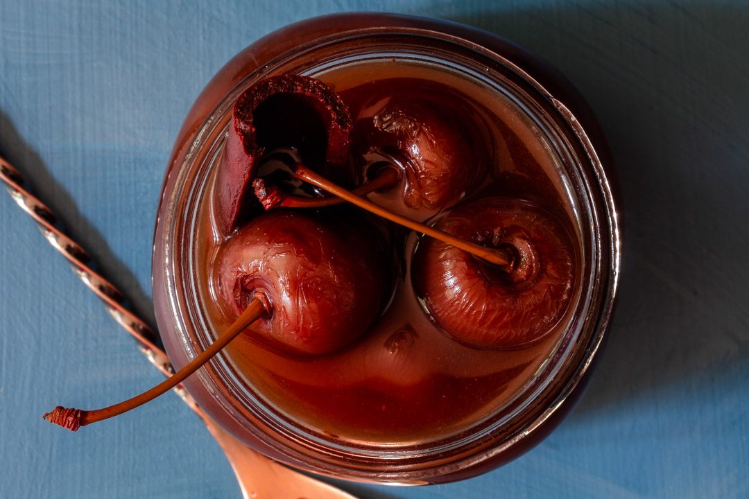 Spiced pickled cherries close up from above with bar spoon