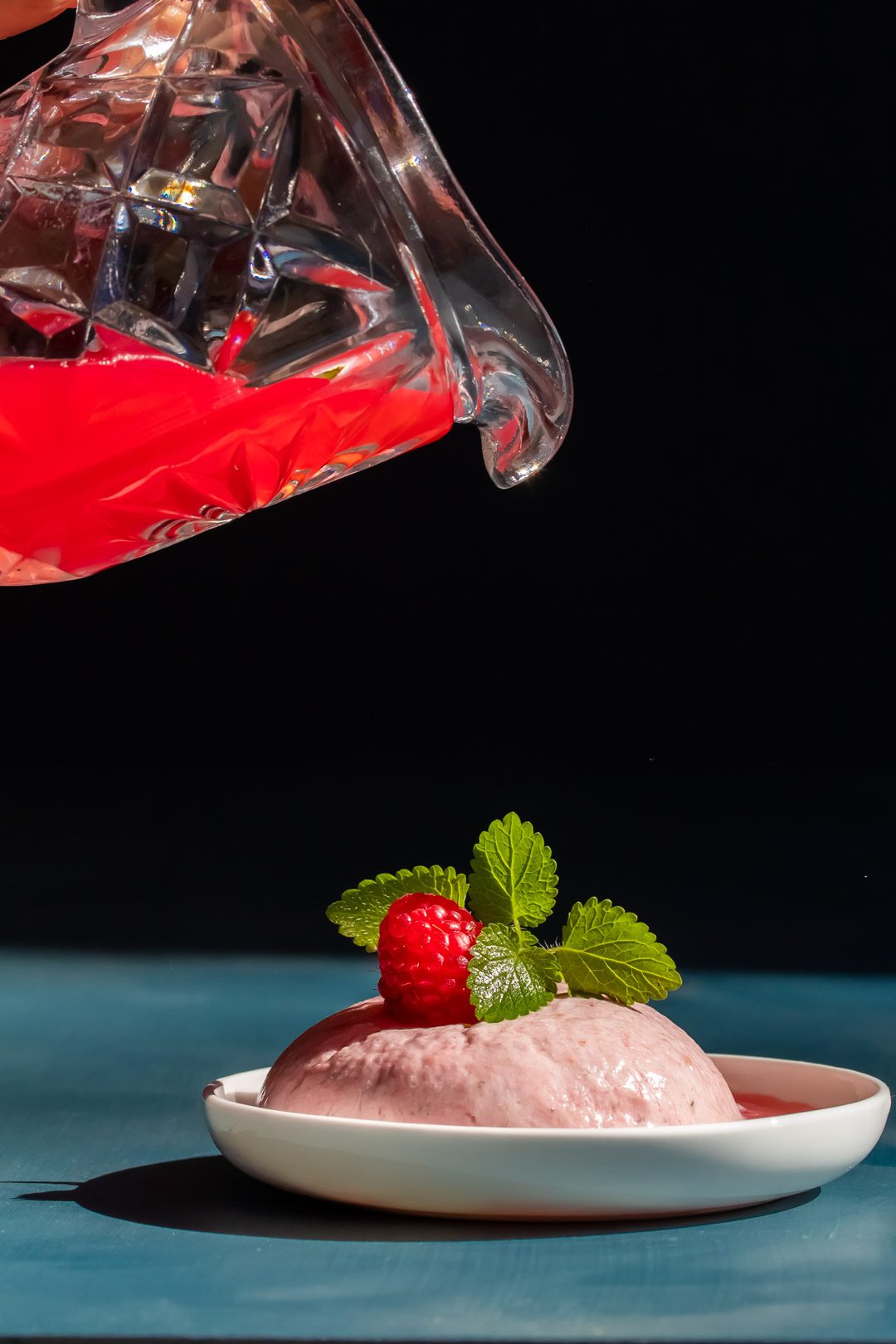 Ice cream made from Raspberry shrub drinking syrup leftovers with jug about to pour syrup