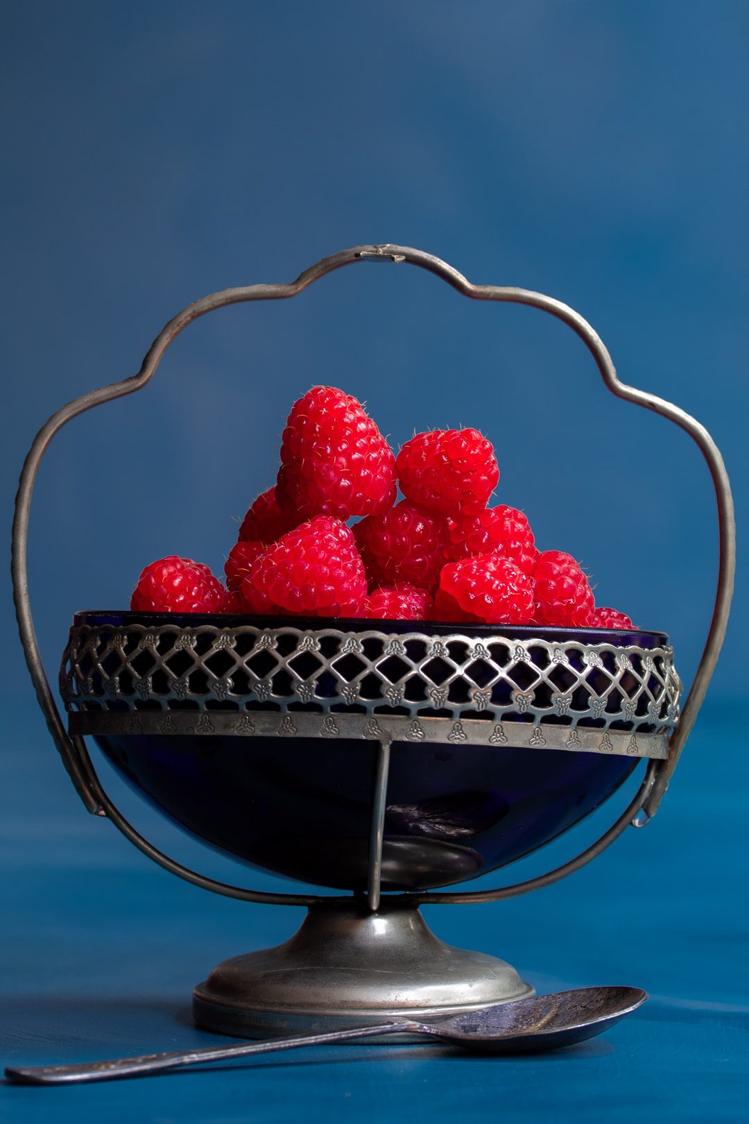 Making Raspberry shrub syrup drinking vinegar with raspberries in blue glass vintage sugar bowl