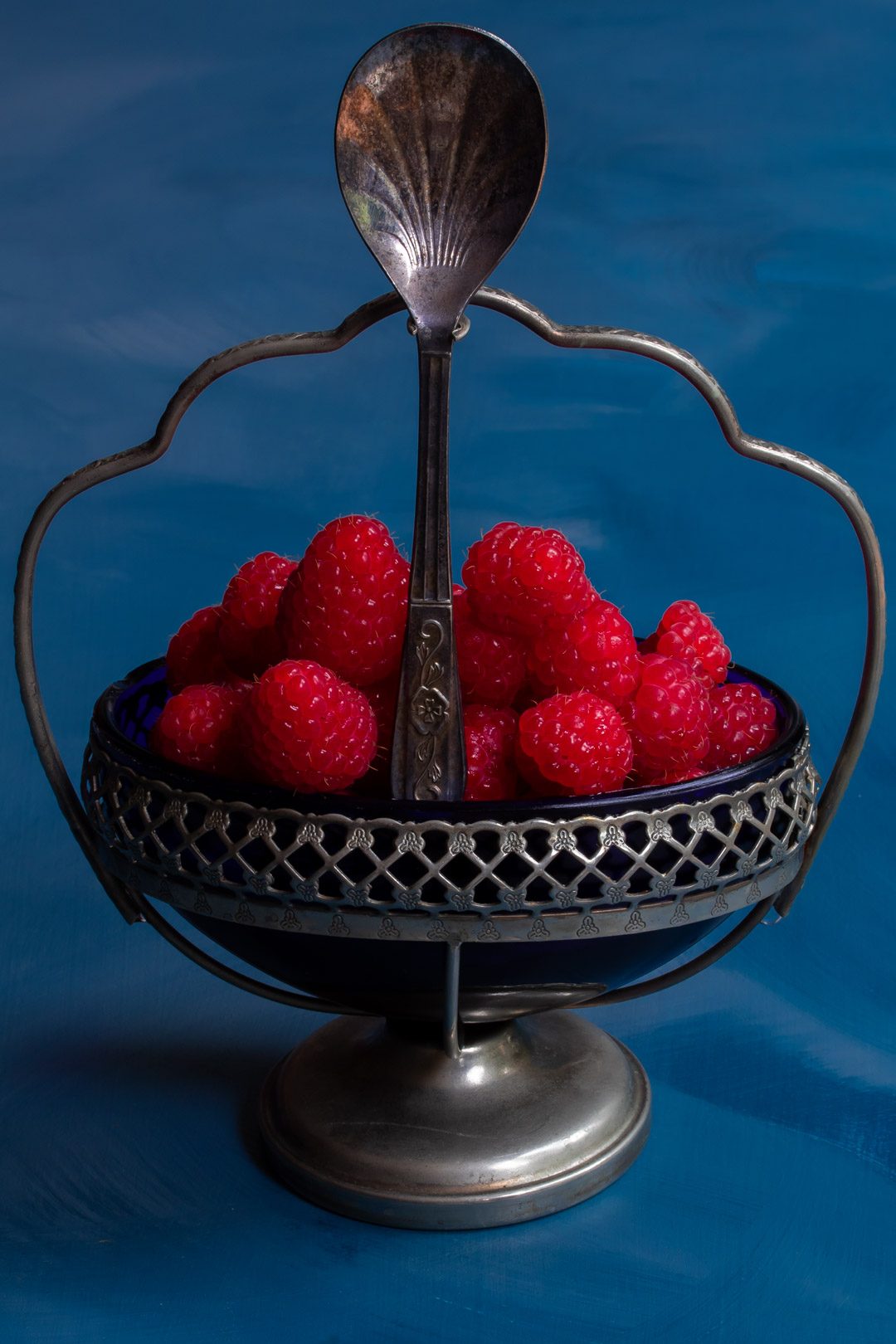 Making Raspberry shrub syrup drinking vinegar with raspberries in vintage blue glass sugar bowl with spoon centre