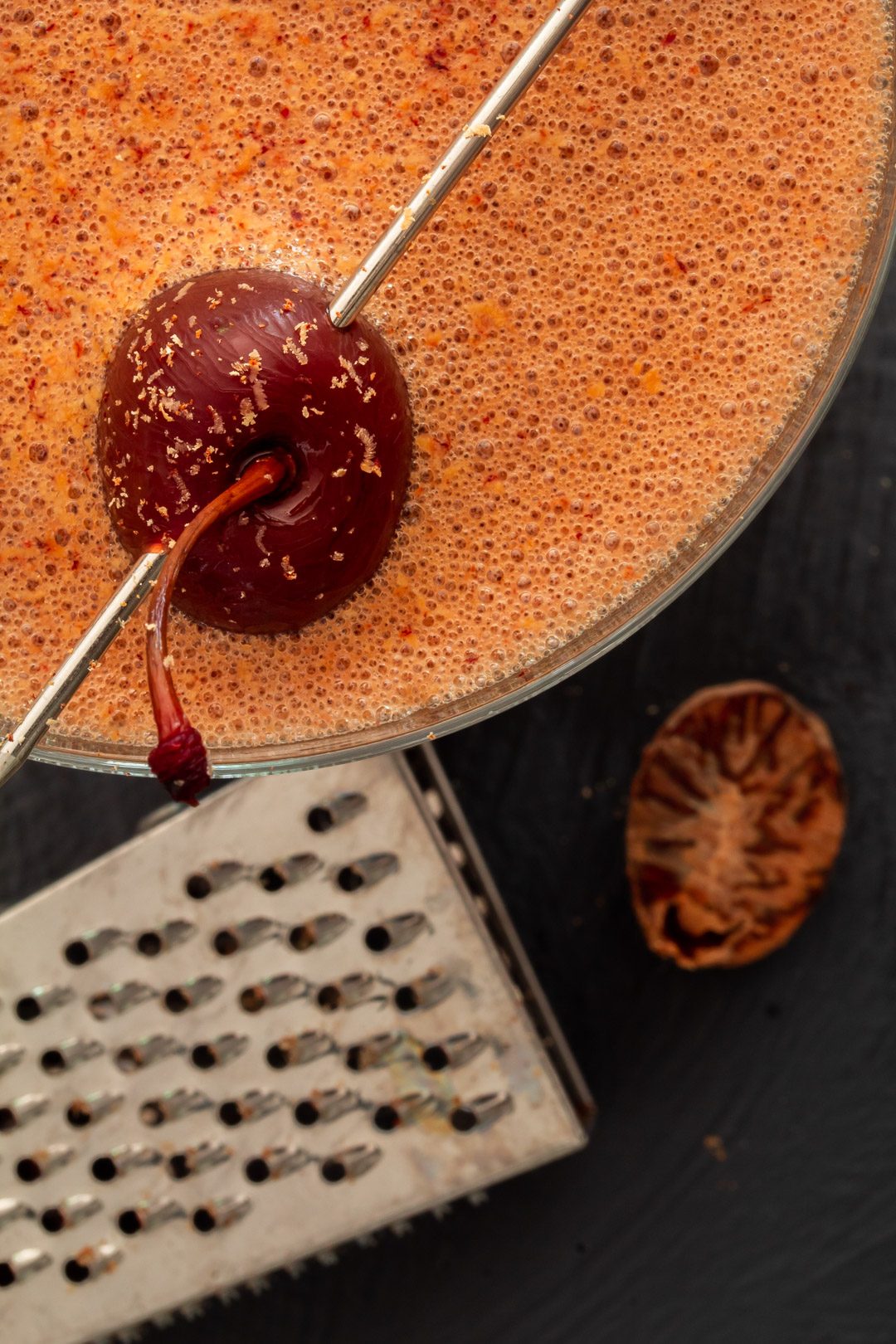 pickled cherry chocolate sherry flip cocktail from above with nutmeg and grater