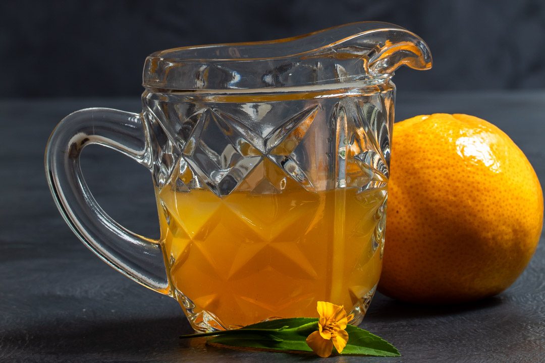 Mandarin tarragon shrub syrup drinking vinegar in antique glass jug horizontal