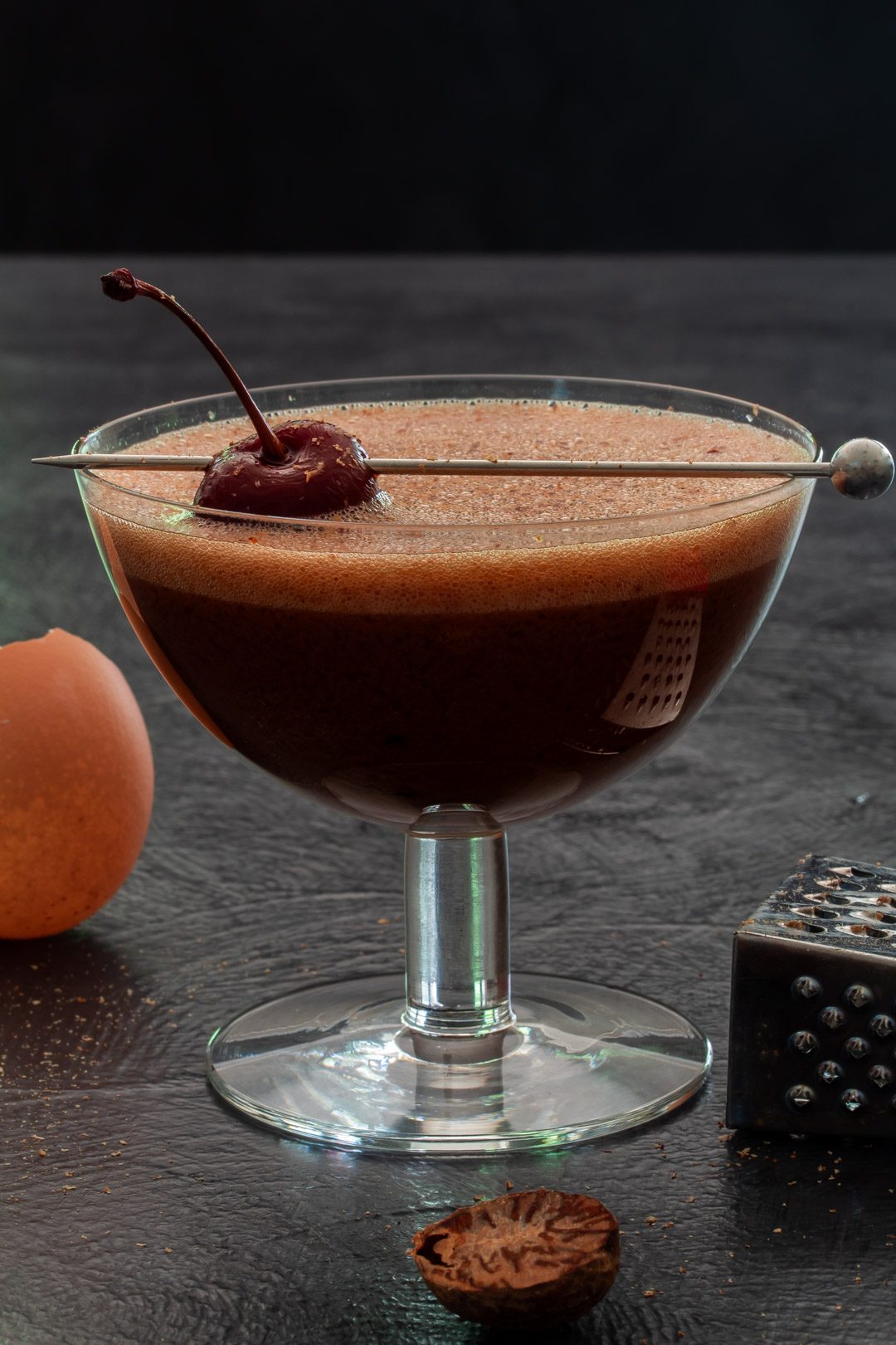 Pickled cherry chocolate sherry flip cocktail with egg shell and nutmeg grater