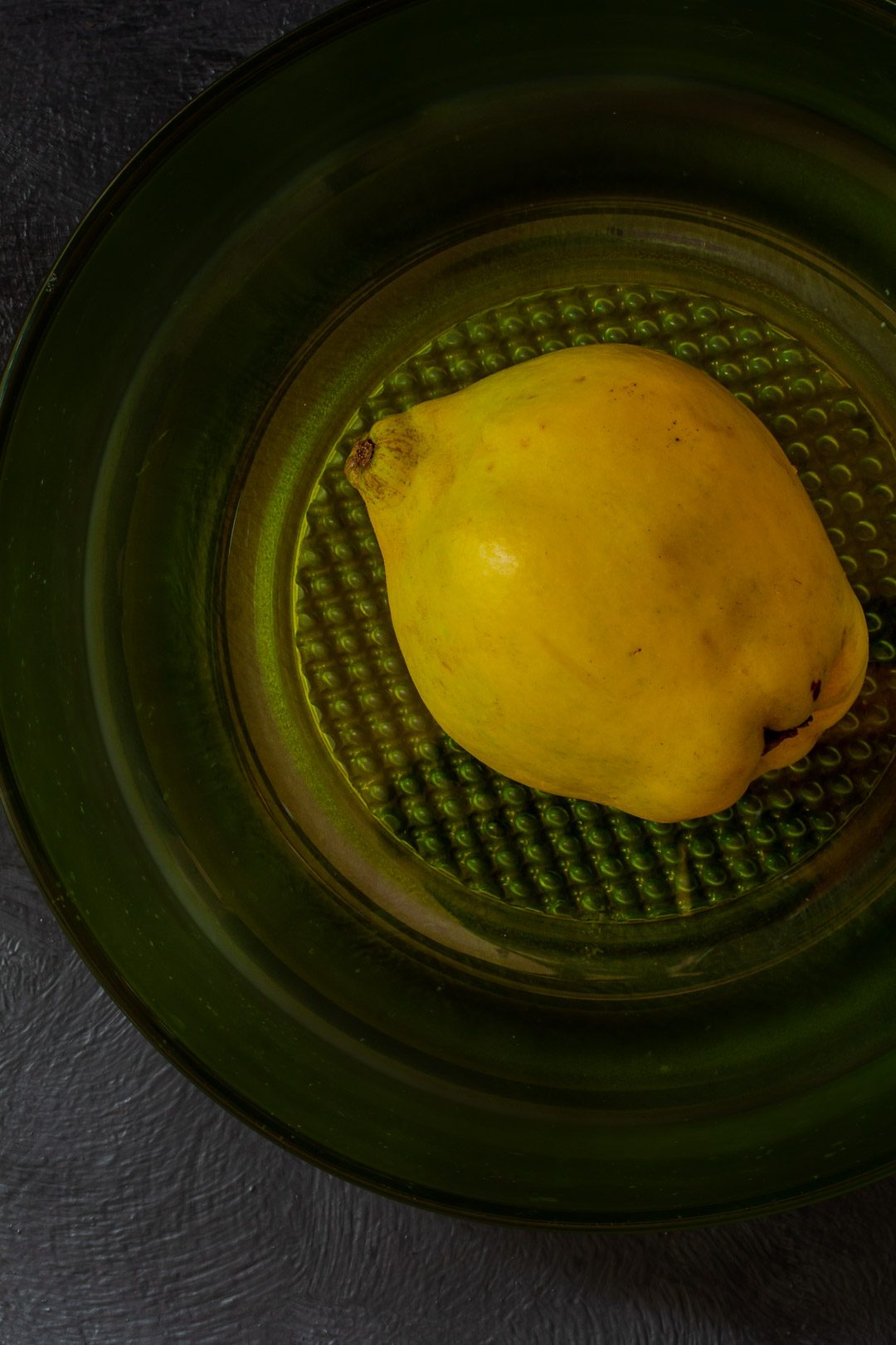 making Vintage Quince Cordial with single quince in green glass bowl