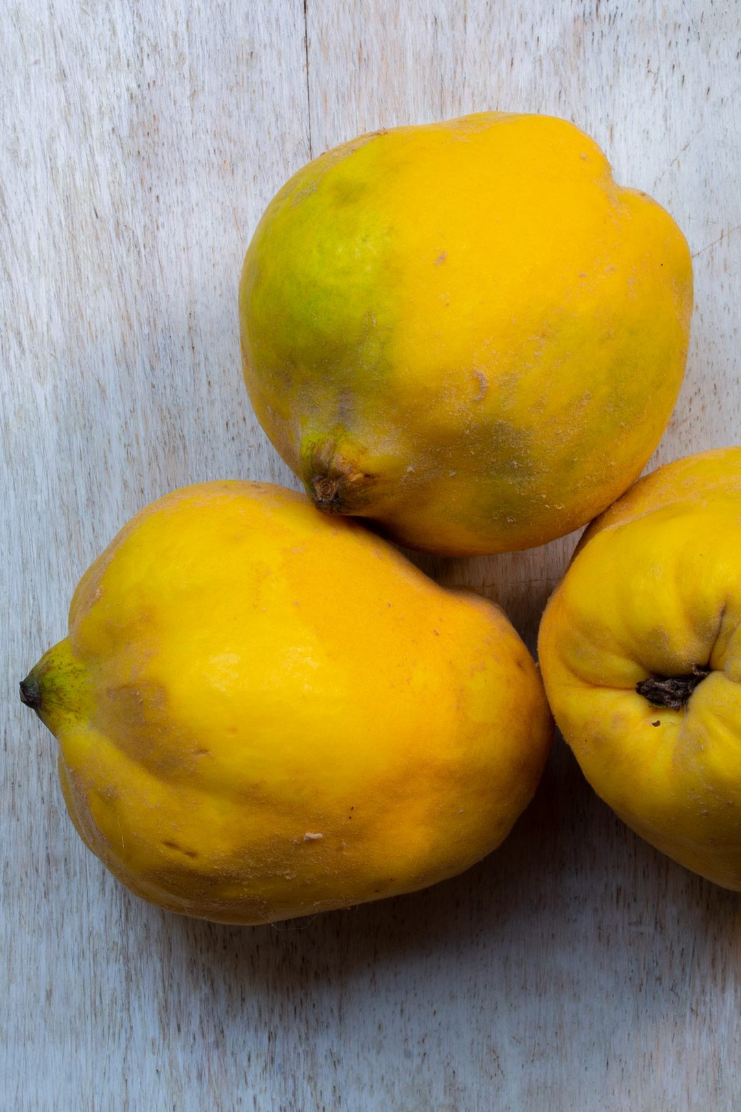 Making Spiced pickled quinces with 3 quinces on white background