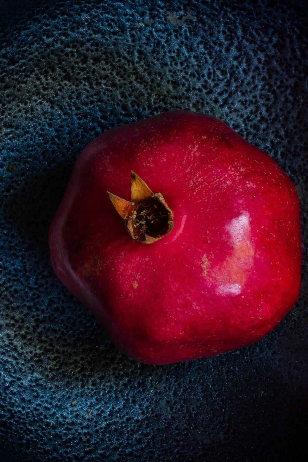 pomegranate on black textured background form above used to make grenadine