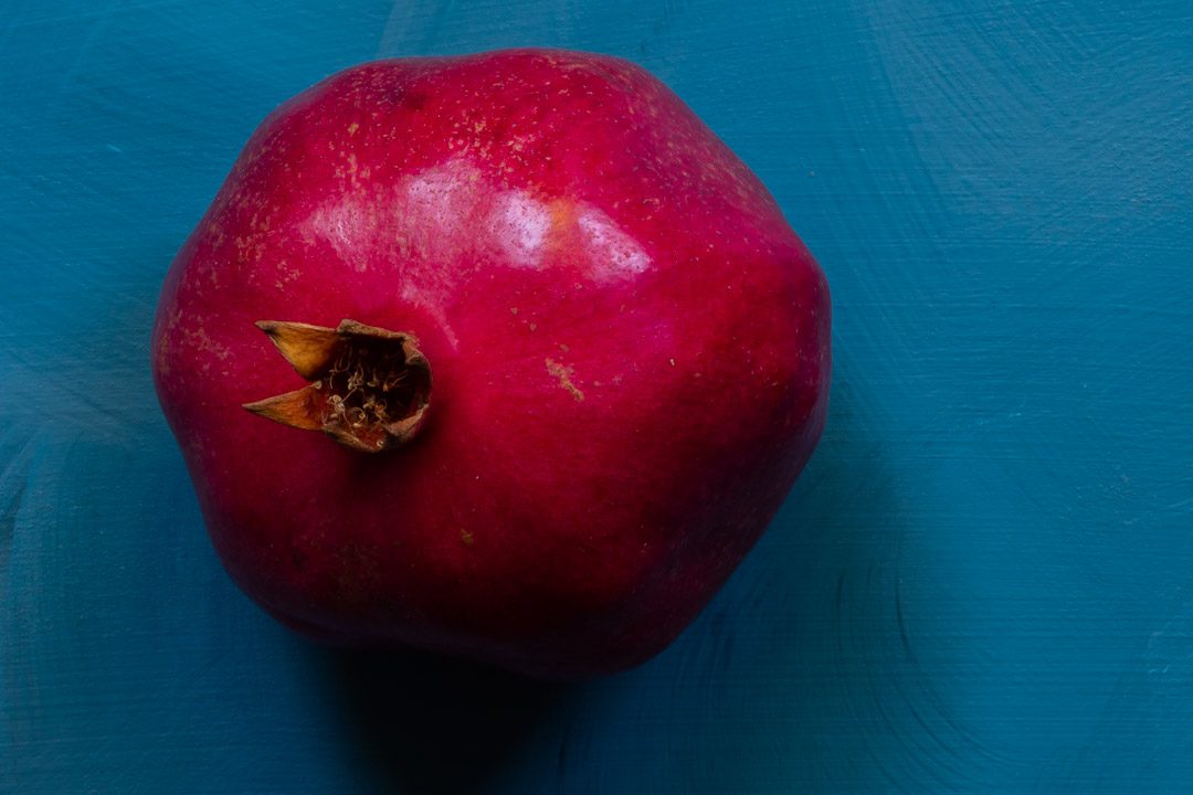 pomegranate on blue background from above used to make grenadine