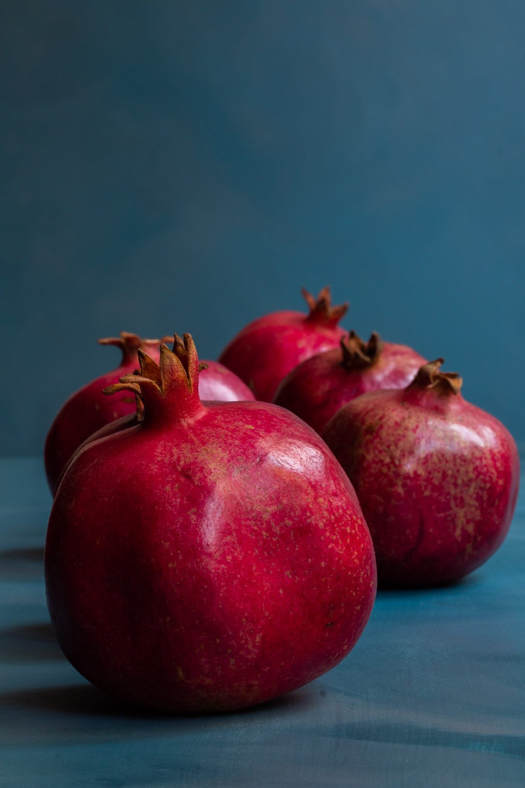 pomegranates in a row on blue background used to make grenadine