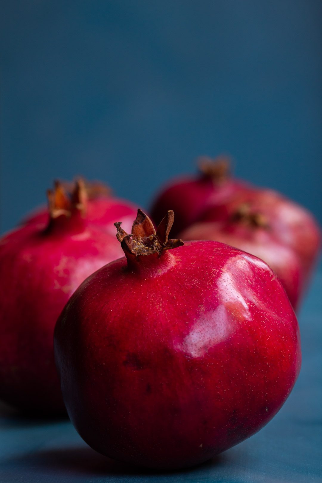 pomegranates in a row close up on blue background used to make grenadine