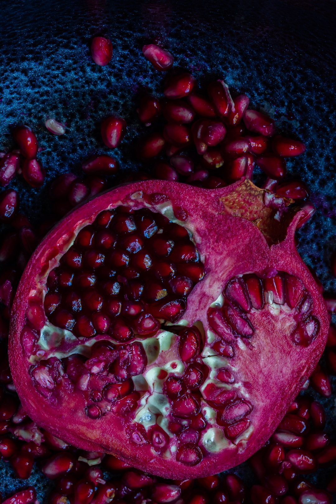 pomegranate split open on black textured background from above used to make grenadine