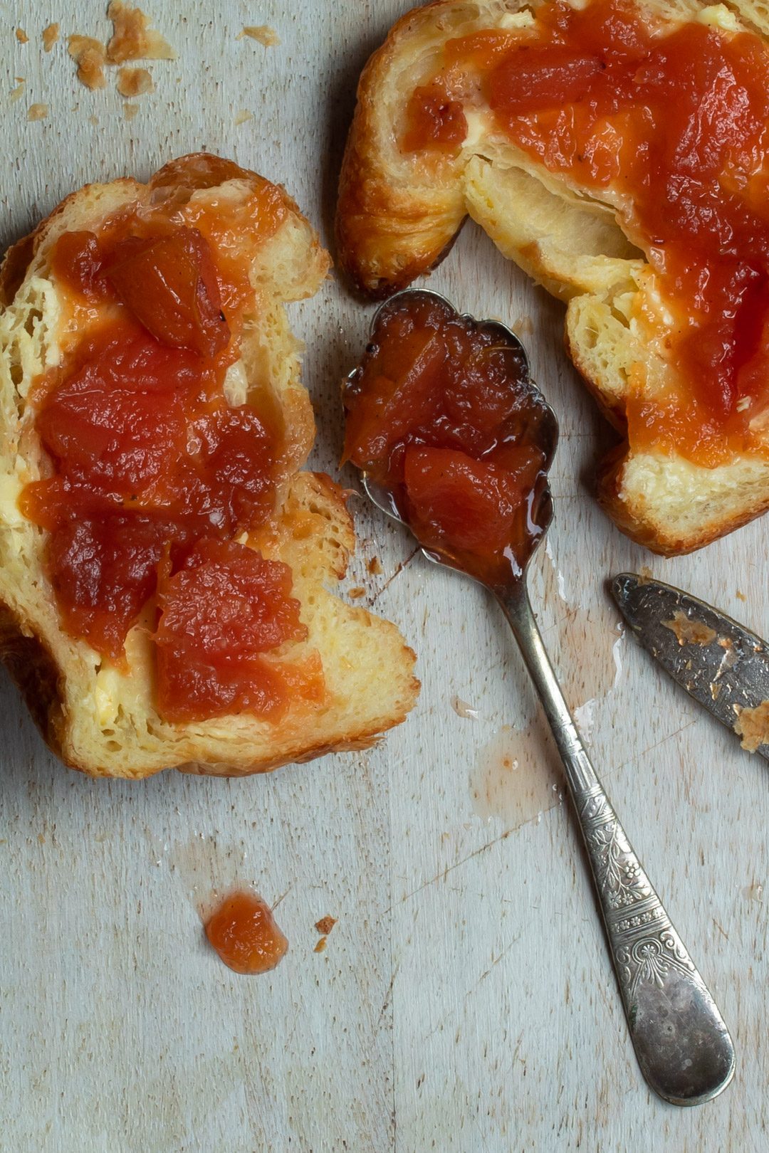 Rustic quince apple jam on a vintage spoon between a split croissant