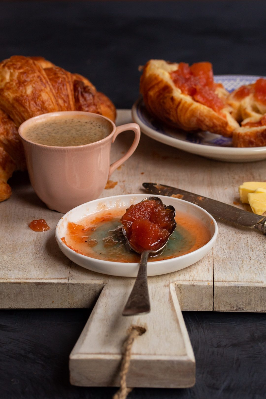 rustic quince apple jam on vintage spoon with croissants and coffee in background