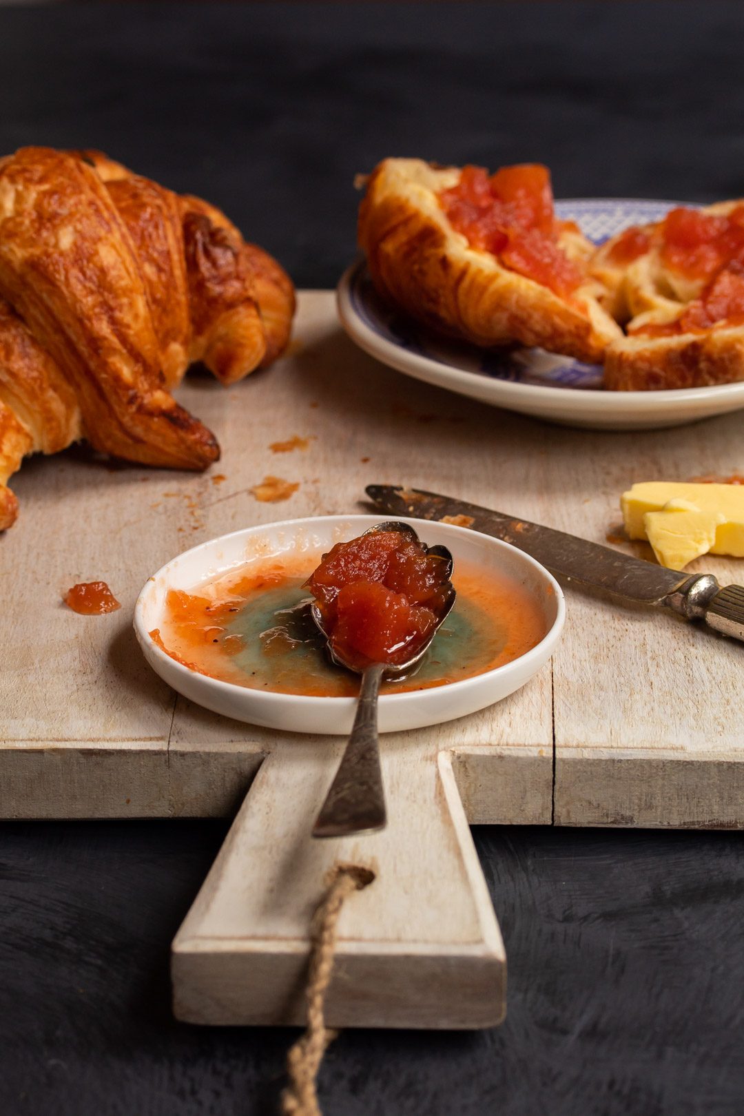 rustic quince apple jam on vintage spoon with croissants in background