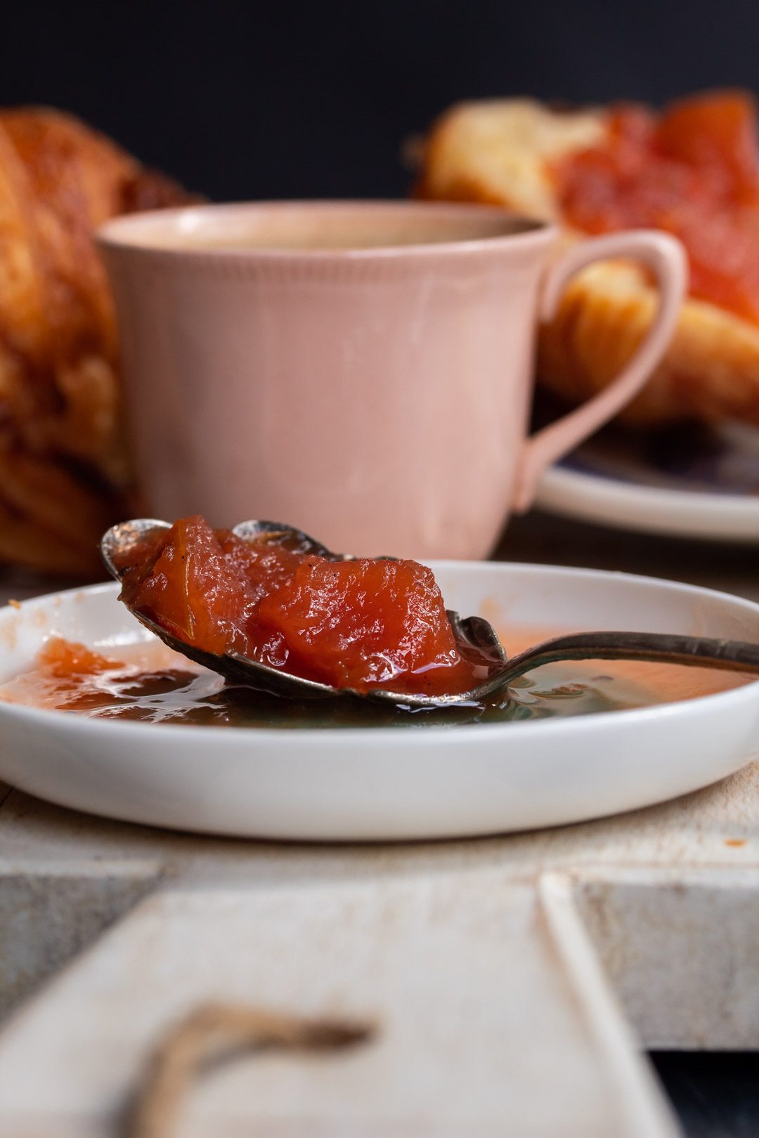 rustic quince apple jam on spoon with pink cup in background