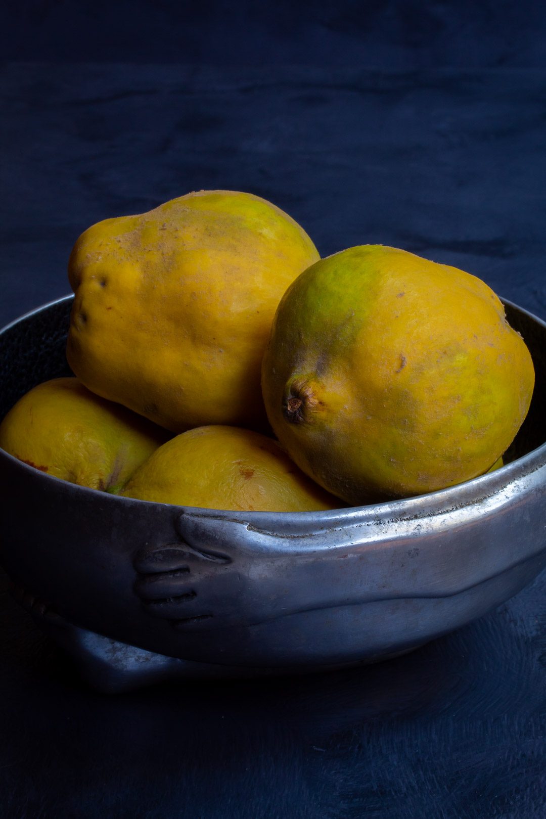 Making spiced pickled quinces with quinces in metal bowl on grey background