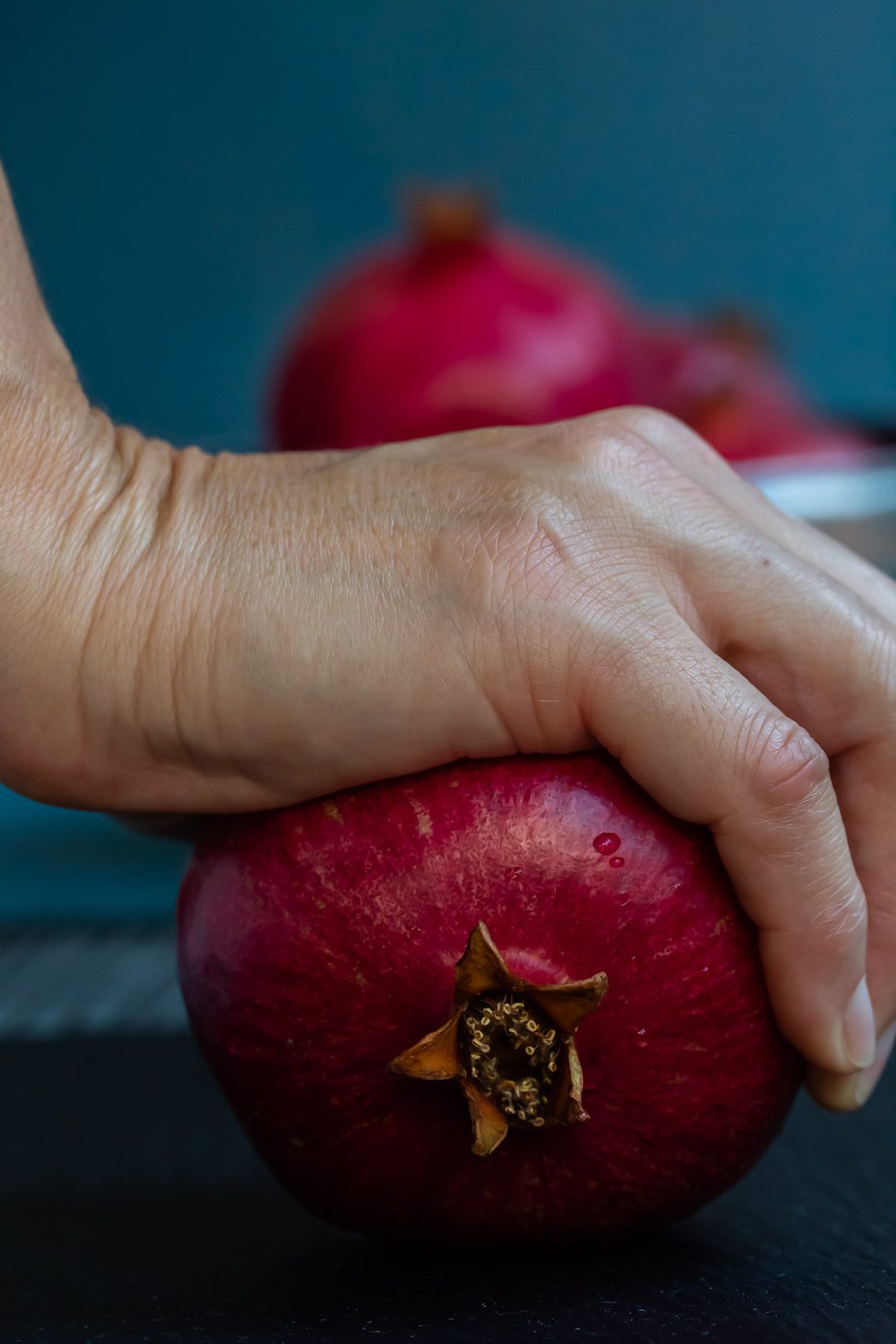 rolling a pomegranate by hand to split the membranes and free the seeds to make grenadine