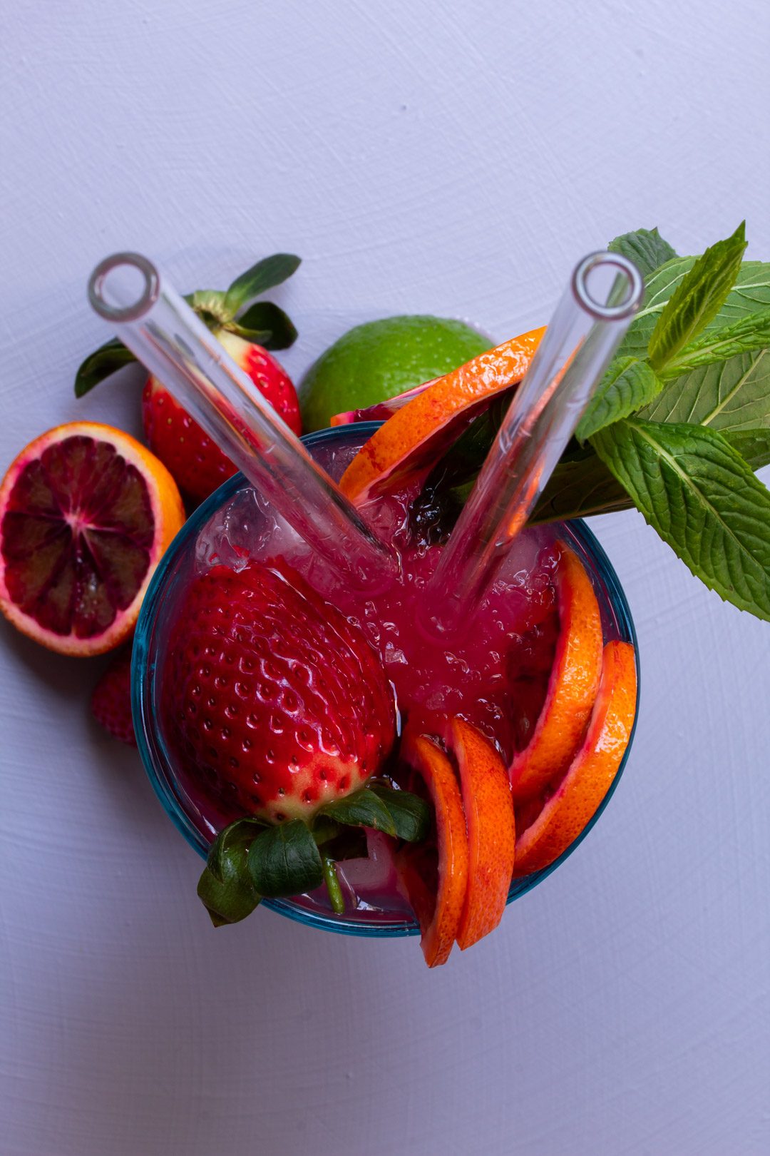 blood orange pomegranate gin daisy cocktail from above on light purple background