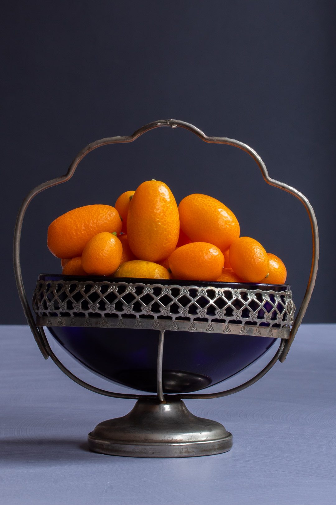 making cumquat brandy with cumquats in vintage blue glass sugar bowl