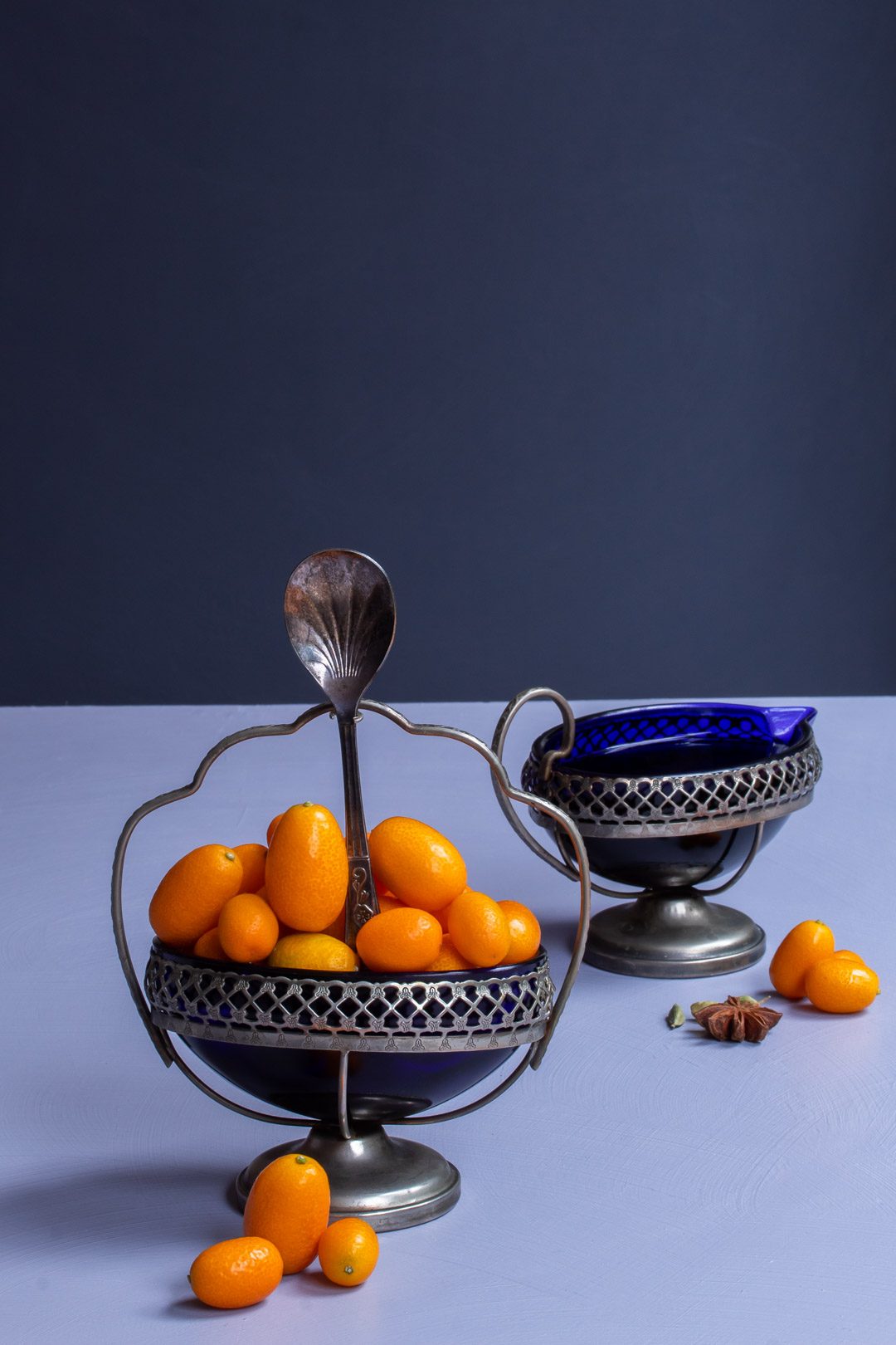 making cumquat brandy with blue glass bowl of cumquats and glass jug of brandy