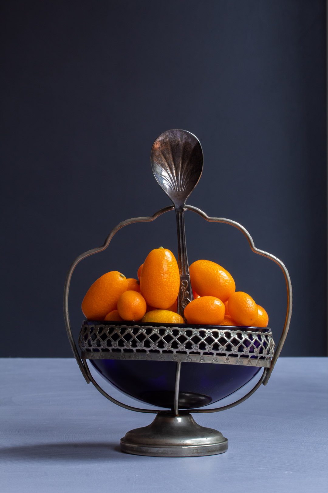 making cumquat brandy with cumquats in blue glass vintage sugar bowl with spoon