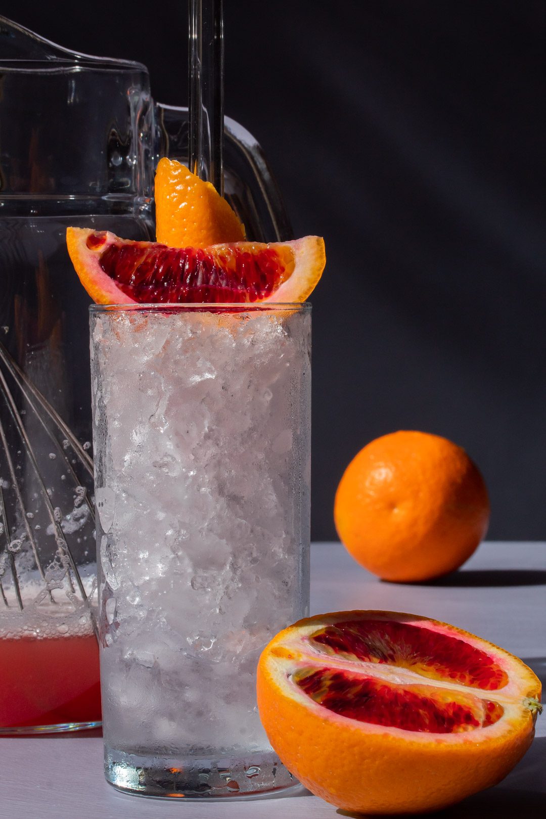 making improved blood orangeade with jug, whisk and orange in background