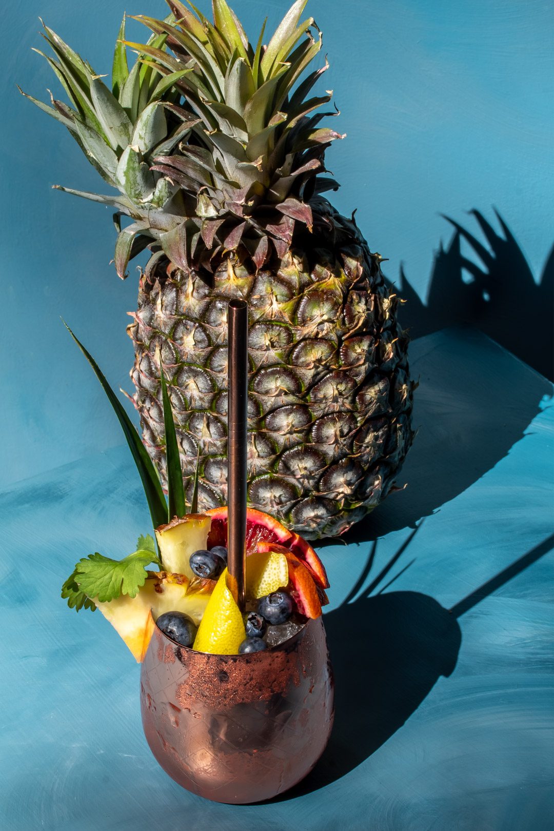 pineapple shrub gin fix cocktail with pineapple and shadows in background