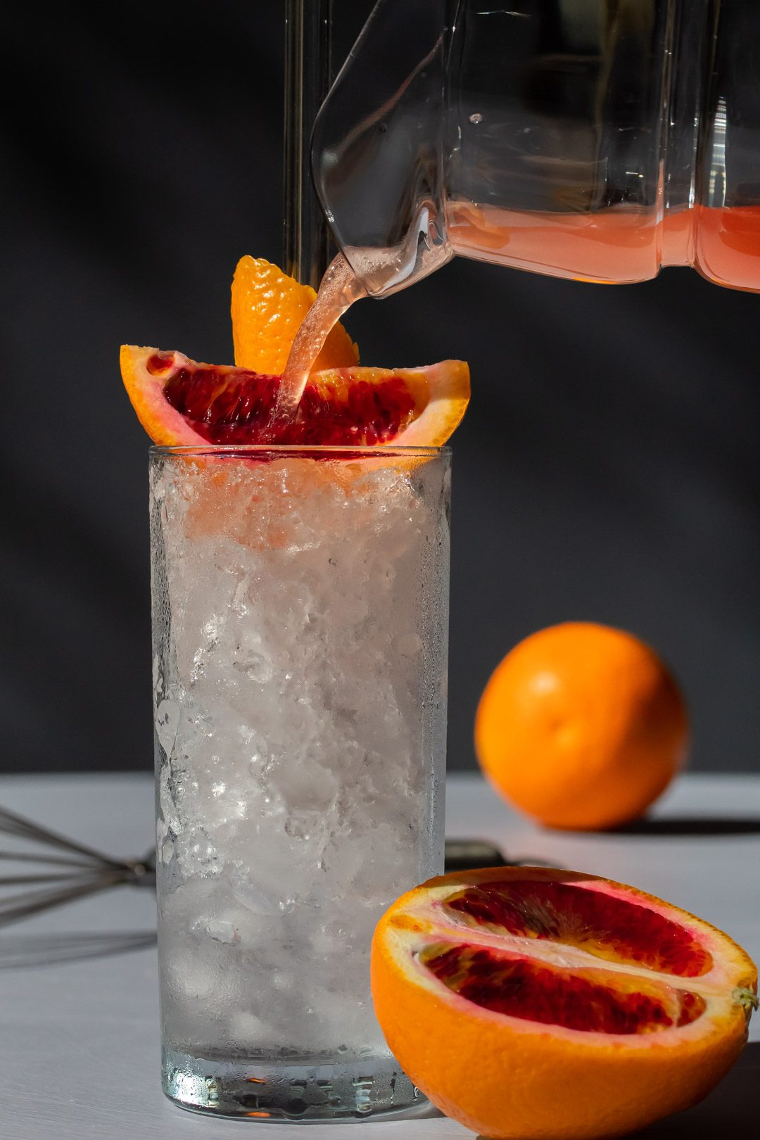 improved blood orangeade being poured into glass of crushed ice