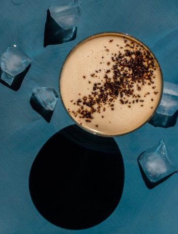 Quince Wattleseed Alexander Cocktail with ice on blue background