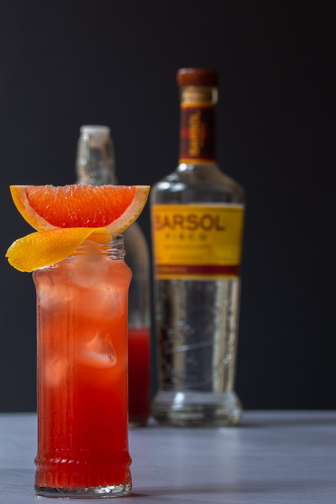 Strawberry ginger beer Chilcano de pisco with pisco and ginger beer bottles in background