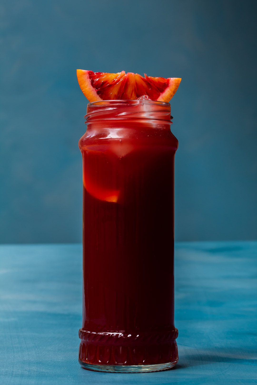 pickle blood orange Americano cocktail isolated on blue background