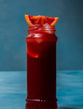 pickle blood orange Americano cocktail isolated on blue background