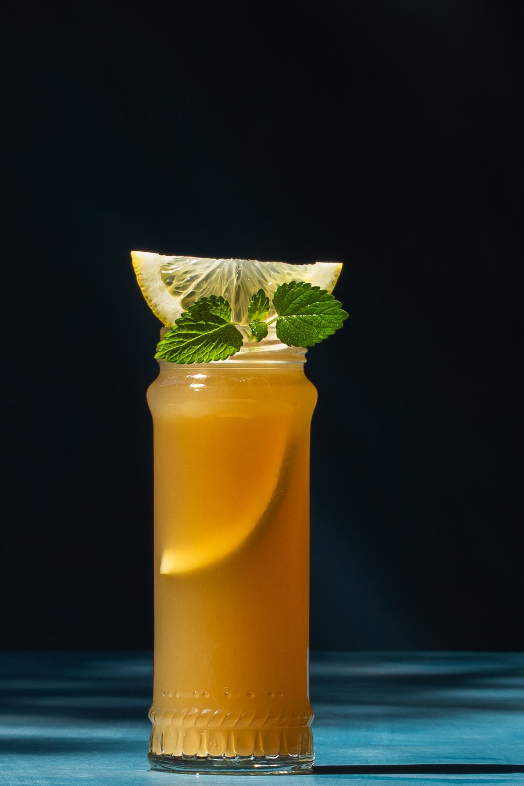 Pickle Gin Buck Cocktail on blue background to left with shadows