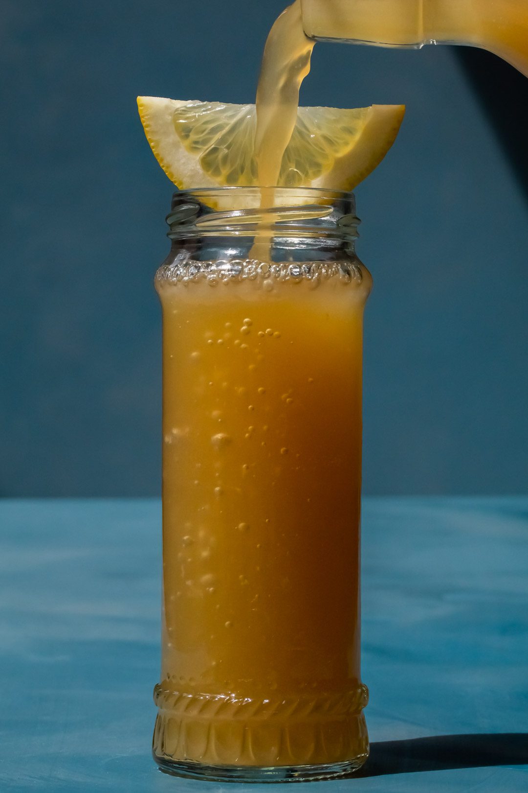 pouring ginger beer into a full Pickle Gin Buck Cocktail