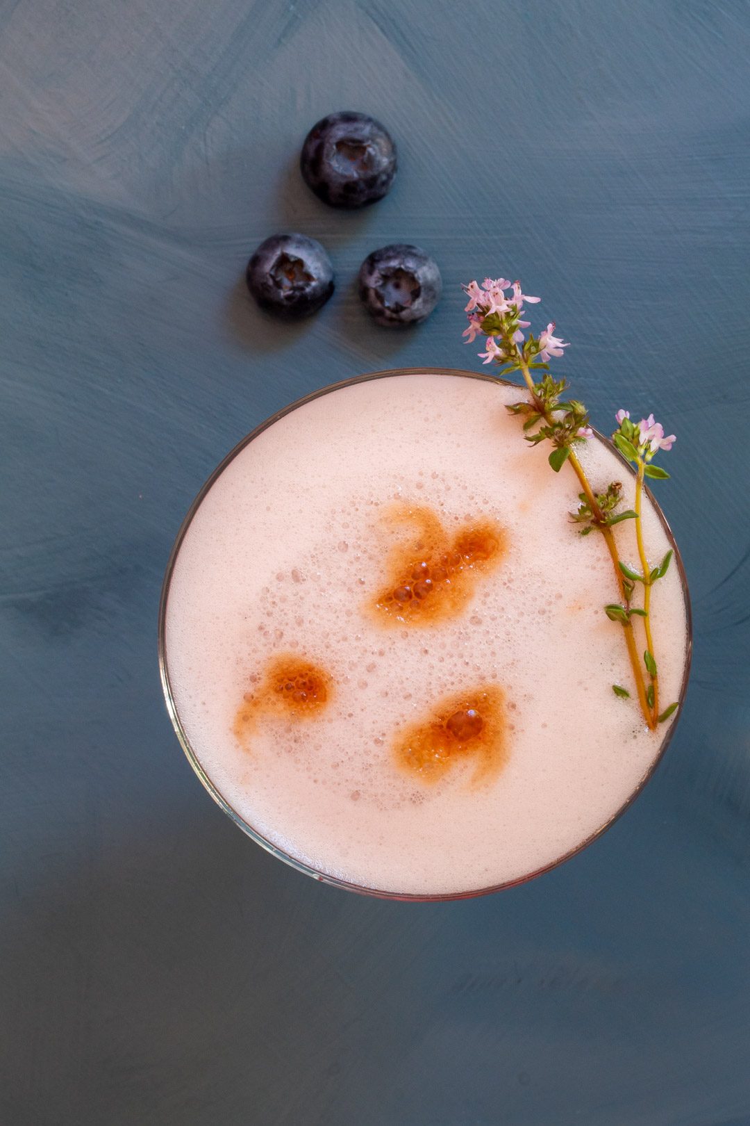 blueberry shrub pisco sour cocktail with thyme, blueberries and bitters from above