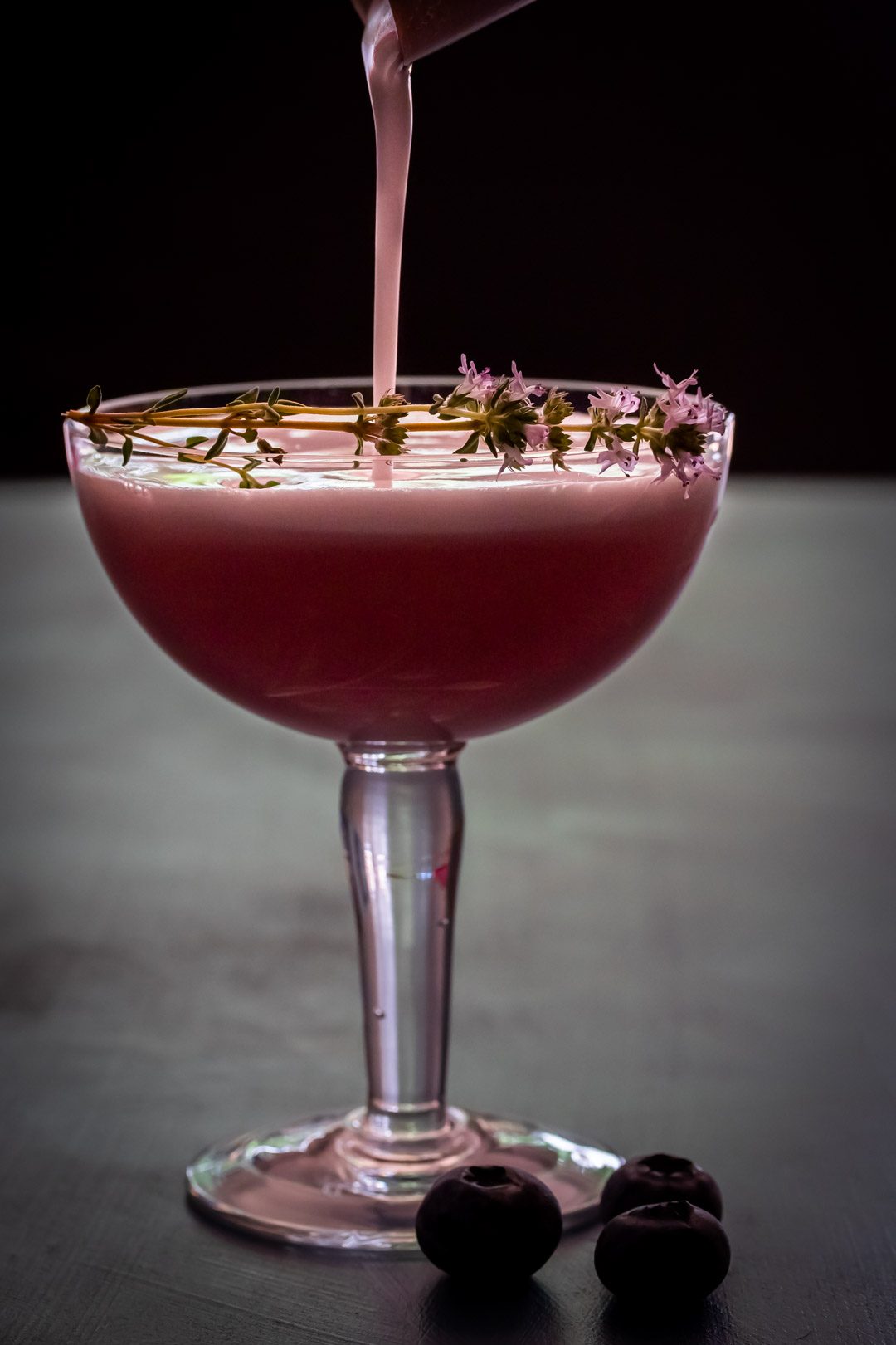 pouring a blueberry shrub pisco sour cocktail