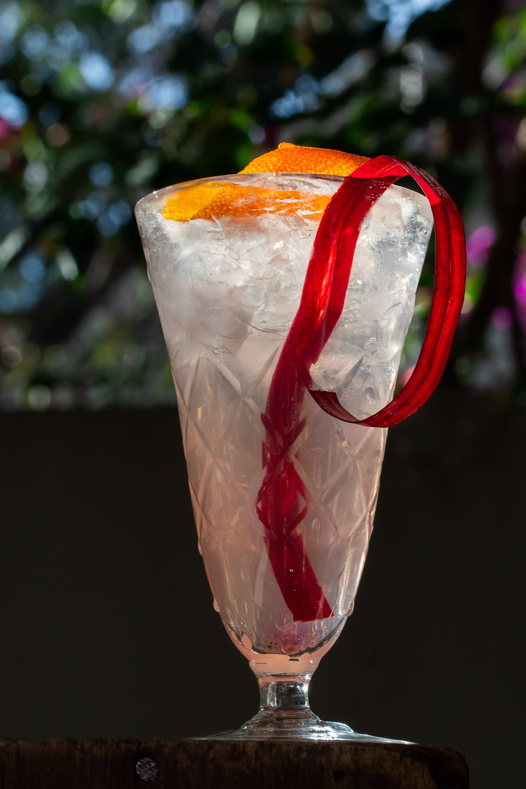 rhubarb shrub gin fix cocktail with rhubarb ribbon and orange twist garnish to side