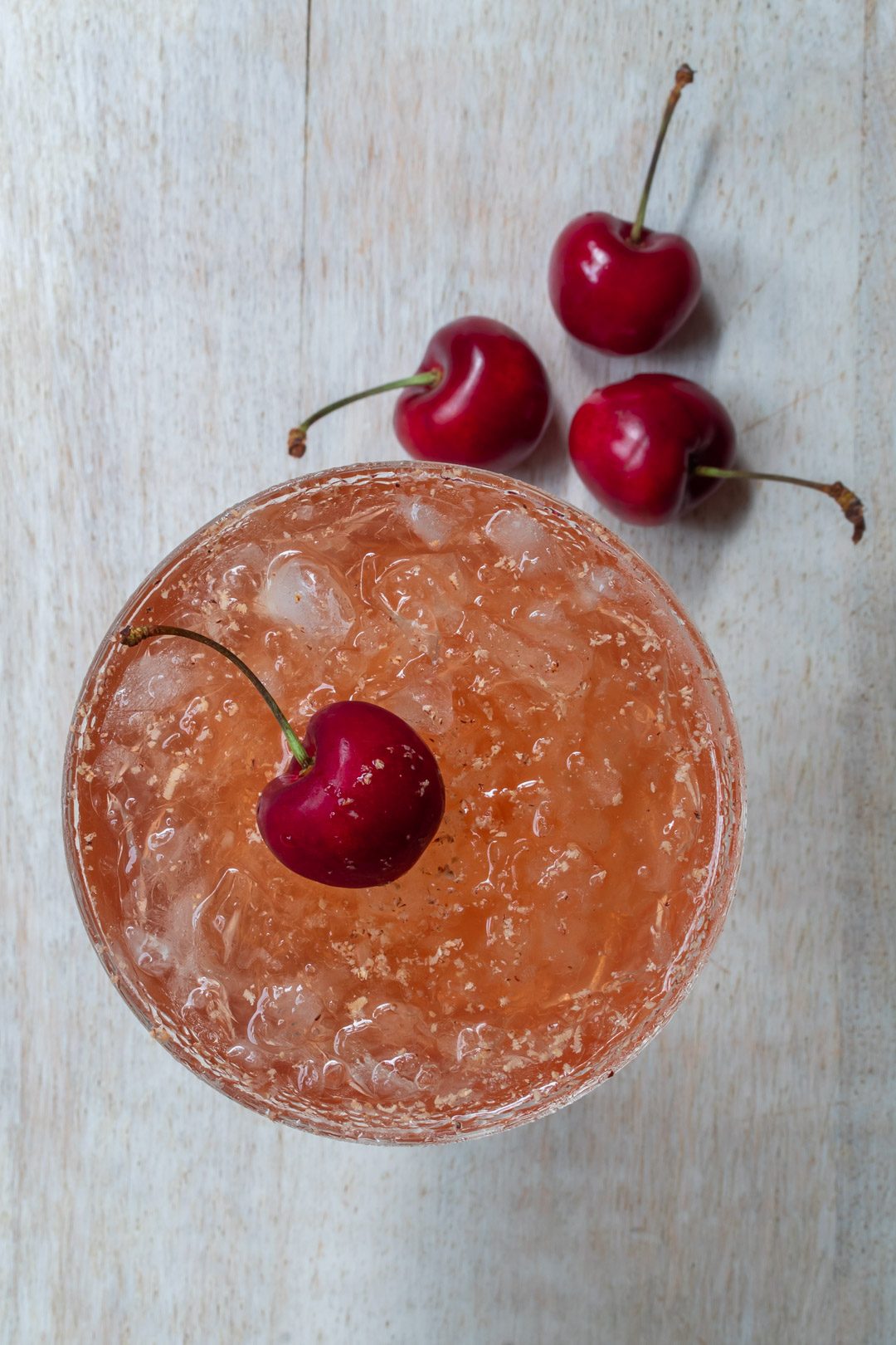 cherry shrub brandy daisy on white board with cherries from above