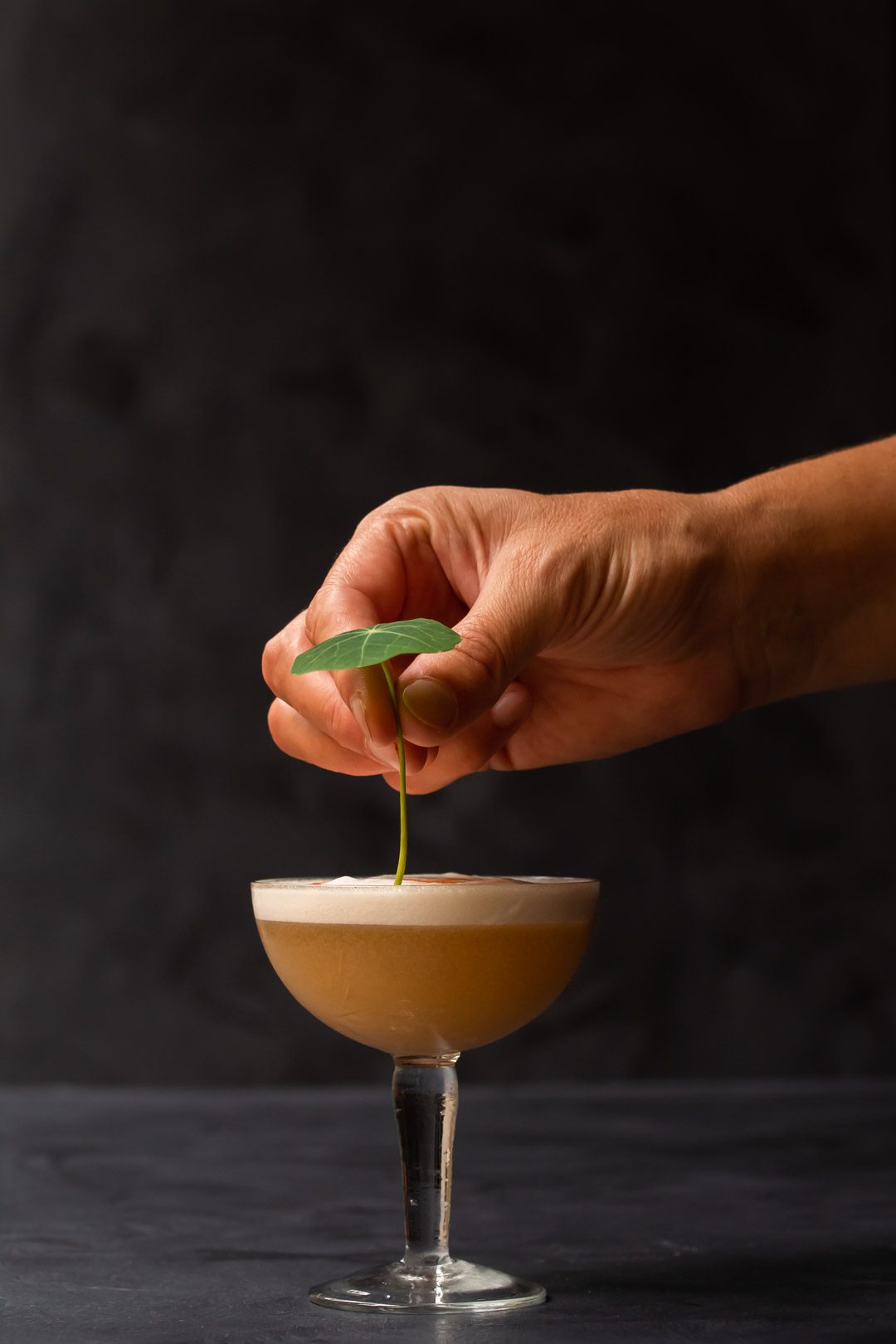 adding a nasturtium leaf garnish to honey rhubarb silver sour