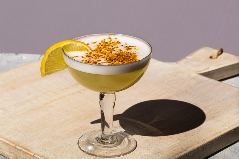 bee's knees silver sour with bee pollen and lemon garnish